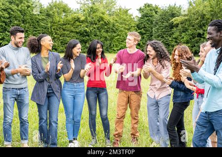 Amici multirazziali che batte le mani, gruppo vario di gente felice alla riunione esterna, concetto multiculturale e di diversità Foto Stock