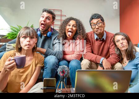 Grimacing generationz z persone, giovani blogger felici smart filmare nuovi video vlog con smartphone e computer portatile a casa, giovani che hanno divertimento e broa Foto Stock