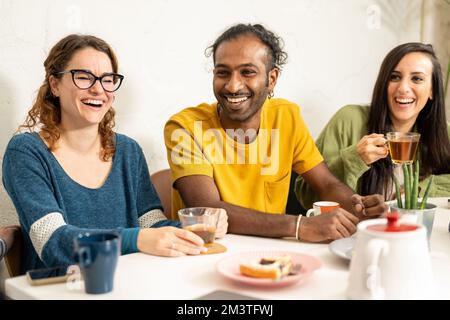 Felice ritrovo di giovani amici nella caffetteria, studente universitario multirazziale che ha funa a colazione Foto Stock