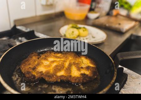 Cucina polacca. Processo di frittura di cotoletta di maiale trita. Pezzo di carne su una padella con grasso. Ritratto interno. Foto di alta qualità Foto Stock