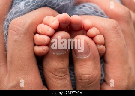 La madre sta facendo il massaggio sul suo piede del bambino. Piedi del bambino del primo piano nelle mani della madre. Foto Stock