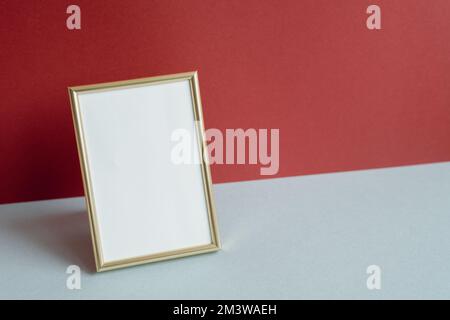 Cornice fotografica dorata con spazio vuoto bianco. biglietto di auguri. sfondo rosso e grigio Foto Stock