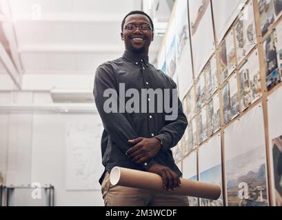 Im sicuro nel lavoro che faccio. Ritratto corto di un bel giovane architetto maschio sorridendo mentre tiene un rotolo di blueprints in un moderno Foto Stock