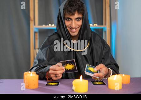 Uomo fortuna che legge il futuro da tar carte seduta a un tavolo con candele. Spazio di copia Foto Stock