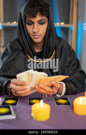 Maschio Fortune Teller lettura di un futuro da carte tarocchi alla luce del concetto di candela. Foto Stock