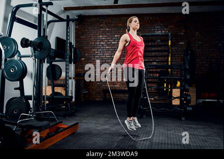 Ottenere il sangue che pompa. Scatto completo di una giovane atleta che salta in palestra. Foto Stock