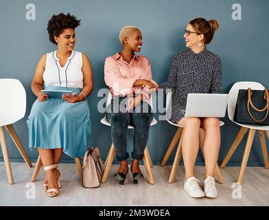Ci incontriamo di nuovo. Studio shot di due attraenti giovani donne d'affari che scuotono le mani mentre si siedono in linea su uno sfondo grigio. Foto Stock