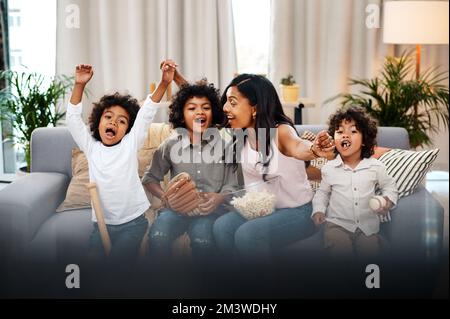 La nostra squadra preferita è vincente. tre adorabili ragazzini che guardano una partita di baseball in tv a casa loro madre. Foto Stock