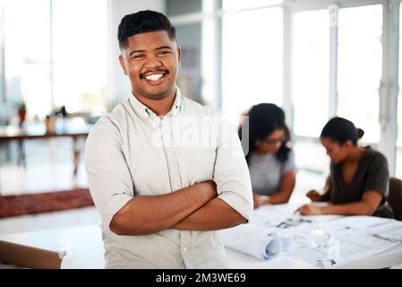 Determinato a progettare il meglio. Ritratto di un giovane uomo d'affari fiducioso in piedi davanti ad un team di architetti. Foto Stock