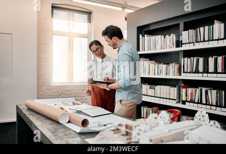 Trova l'app giusta e inizia a progettare. due aspiranti giovani architetti che utilizzano un tablet digitale mentre lavorano insieme in un ufficio moderno. Foto Stock