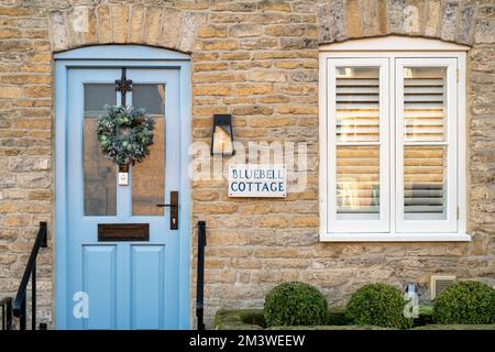 Corona di Natale su una porta di un cottage in pietra. Riposto sul Wold, Cotswolds, Gloucestershire, Inghilterra Foto Stock