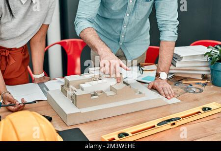 La loro creazione sarà la più riuscita mai. Primo piano di due architetti che lavorano insieme su un modello in scala di un edificio in un ufficio. Foto Stock