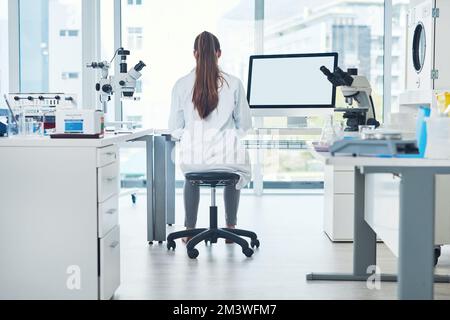 Lavorare duro tomget. Ripresa retrofisiva di una giovane scienziata concentrata che conduce esperimenti all'interno di un laboratorio durante il giorno. Foto Stock