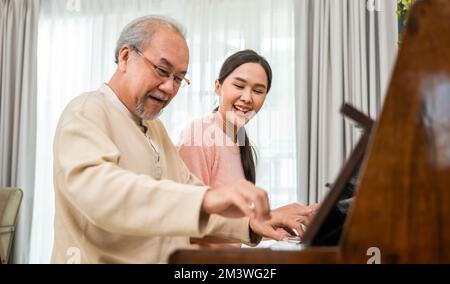 Giovane donna che insegna pianoforte per l'insegnamento di alto uomo Foto Stock