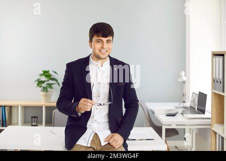 Ritratto di un uomo d'affari giovane, di successo e fiducioso che si pone in ufficio di impresa. Foto Stock