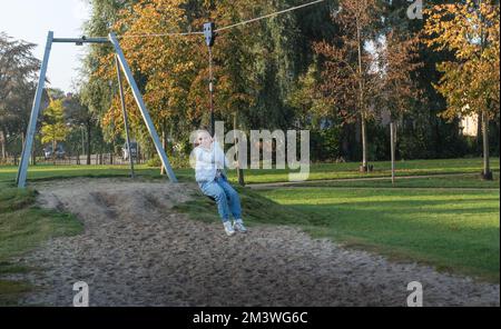 divertimento all'aperto. giovane ragazza in sella a un bungee appeso sul parco giochi Foto Stock