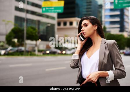 Mi sto facendo strada subito. una giovane e attraente donna d'affari che prende una telefonata mentre si viaggia in città durante il giorno. Foto Stock