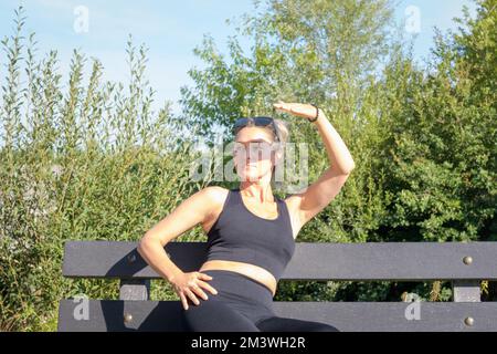 Sport all'aperto in una giornata calda. Giovane donna copre il suo volto con la mano dal sole luminoso Foto Stock