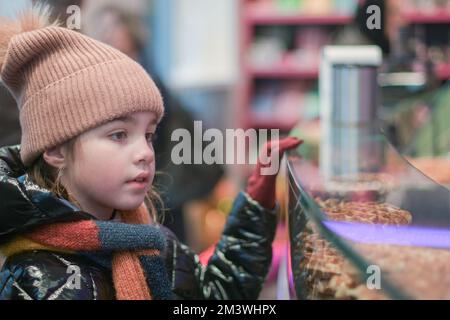 La ragazza alla finestra con dolci. Negozio di dolciumi in inverno Foto Stock