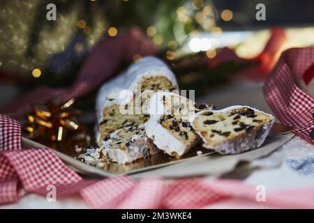 Stollen di Natale, conosciuto come Christstollen - pane classico di Natale. Tradizione natalizia con sfondo bokeh. Sfondo festivo. Foto Stock