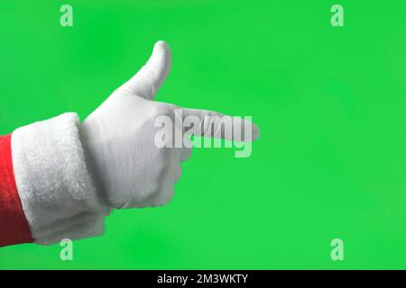 Mano di Babbo Natale che indica la parte anteriore con il dito indice isolato su sfondo verde. Primo piano. La mano bianca con un guanto indica in avanti qualcosa con su Foto Stock