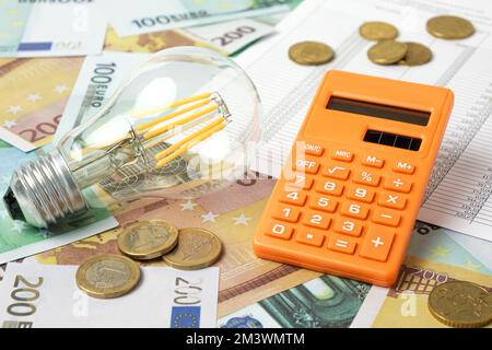 Spina di alimentazione e calcolatrice sulle banconote in euro sfondo. Aumento dei consumi. Costo dell'elettricità, concetto di energia costoso. Escursione dei prezzi. Riscaldamento Cri Foto Stock