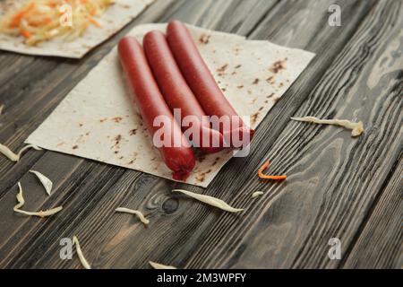 Salsicce affumicate, cavolo e pane pita isolato su sfondo di legno Foto Stock