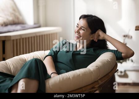 Allegro bella giovane donna proprietario di casa riposante in morbida poltrona elegante Foto Stock