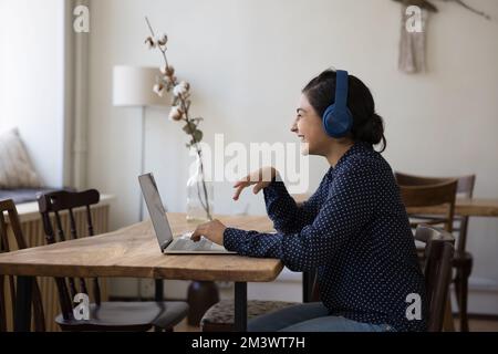 Allegra ragazza studentesca indiana adulta in cuffie ridendo di laptop Foto Stock