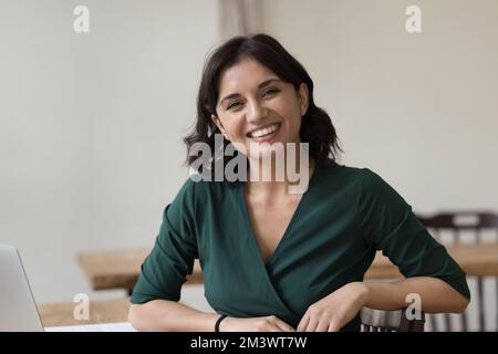 Felice donna di successo di affari seduta al tavolo di lavoro Foto Stock