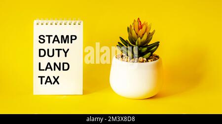 SDLT - Stamp Duty for Land Tax è scritto su un notebook su uno sfondo giallo Foto Stock