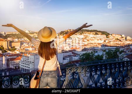 Una donna turistica felice si affaccia sul colorato centro storico di Alfama della città di Lisbona Foto Stock