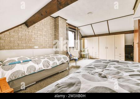 una camera da letto con un letto, comò e tv nell'angolo sul lato sinistro della stanza è un vecchio muro di mattoni Foto Stock