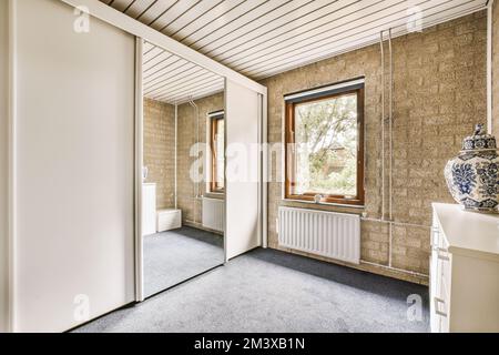 una stanza con una porta aperta e un vaso sul pavimento di fronte alla porta, accanto a un gabinetto Foto Stock