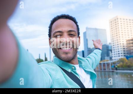 Giovane afro-americano che prende un selfie sorridendo felice mostrando la nuova città in cui vive. Foto Stock