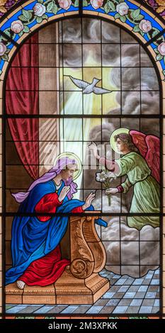 DOMODOSSOLA, ITALIA - 19 LUGLIO 2022: L'Annunciazione sulla vetrata nella chiesa dei Santi Gervasio e Protasio di Luigi Fontana Foto Stock