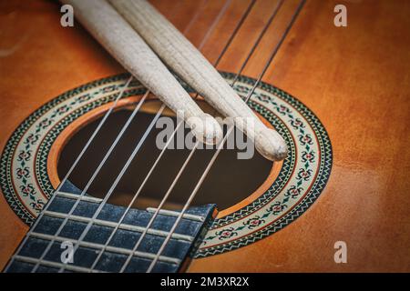 Bastoncini poggiati sulle corde di chitarra Foto Stock