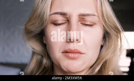 Ritratto di donna piangente di 30 anni. Dolore di tristezza con lacrime agli occhi e mento storto di donna bionda ad occhi chiusi. Emotivo Foto Stock