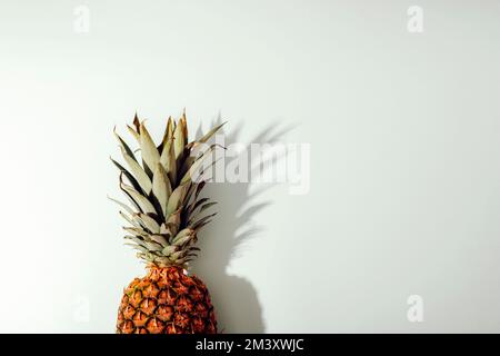 Bordo a ananas su sfondo bianco con ombre dure. Vista dall'alto, disposizione piatta, spazio di copia. Foto Stock