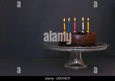 torta al cioccolato con cinque candele colorate. Torta di compleanno con luce candel Foto Stock
