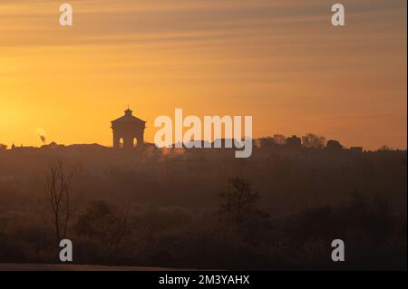 Vista sulla torre dell'acqua di Colchester Jumbo da lontano. Silhouette degli edifici al caldo sole del mattino. Sole che sorge su Colchester, Essex. Foto Stock