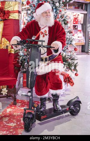 Babbo Natale uomo in cappello abiti di Natale vestito rosso in piedi su scooter con regali. Milano, Italia - Dicembre 2022 Foto Stock