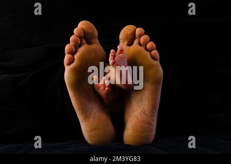 I piedi piccoli di una bambina sono posti tra i piedi di sua madre Foto Stock