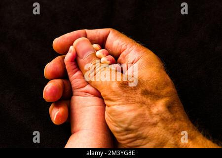 La piccola mano di una bambina è posta nella mano di suo padre Foto Stock