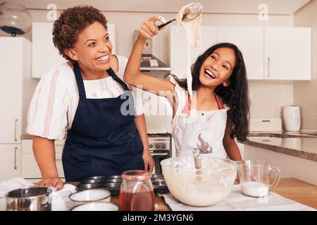 Nonna e graddhaughter che si divertono mentre preparano l'impasto in cucina. Ragazza felice con cucchiaio. Foto Stock