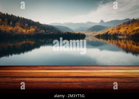 Un tavolo di legno e la foresta d'autunno sfocata e lago in uno sfondo, esposizione di prodotti, montaggio alimentare Foto Stock