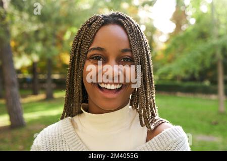 Ritratto di giovane bella donna nera sorridente e guardando la fotocamera all'aperto. Ragazza africana felice. Foto Stock