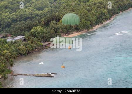 Isola di Murilo, Stati Federati di Micronesia. 06 dicembre 2022. Pacchetti umanitari paracadute a una laguna da un aereo giapponese Air Self-Defense Force C-130H Hercules assegnato al 401st tattico Airlift Squadron, durante l'operazione Christmas Drop, 6 dicembre 2022 a Murilo isola, Chuuuk, Micronesia. Operazione Christmas Drop è la più antica missione umanitaria e di soccorso in caso di disastri che offre 71.000 chili di cibo, regali e forniture per assistere le comunità remote dell'isola nel Pacifico meridionale. Credit: Yasuo Osakabe/US Airforce Photo/Alamy Live News Foto Stock