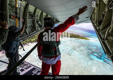 Fananu Atoll, Stati Federati di Micronesia. 09 dicembre 2022. I loadmers dell'aeronautica degli Stati Uniti si lanciano dalla rampa aperta di un velivolo C-130J Super Hercules assegnato allo Squadrone di sollevamento dell'aereo di spedizione 36th, dopo aver lasciato i pacchetti umanitari durante l'operazione Christmas Drop 2022, 9 dicembre 2022 a Fananu Atoll, Chuuuk, Micronesia. Operazione Christmas Drop è la più antica missione umanitaria e di soccorso in caso di disastri che offre 71.000 chili di cibo, regali e forniture per assistere le comunità remote dell'isola nel Pacifico meridionale. Credit: Yasuo Osakabe/US Airforce Photo/Alamy Live News Foto Stock