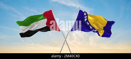 Due bandiere incrociate Bosnia-Erzegovina ed Emirati Arabi Uniti che ondeggiavano nel vento a cielo nuvoloso. Concetto di rapporto, dialogo, viaggio tra tw Foto Stock